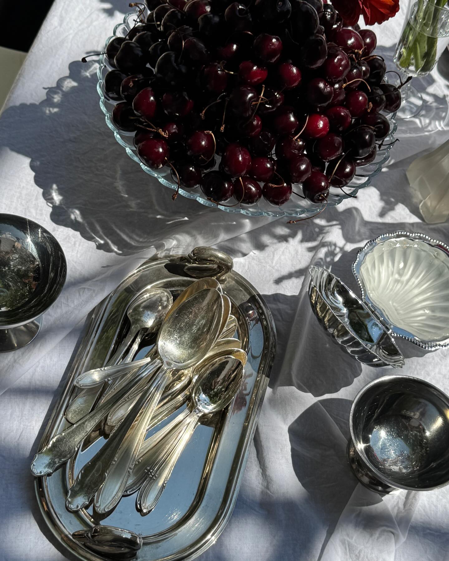Cherries in a glass bowl with silverware on linen
